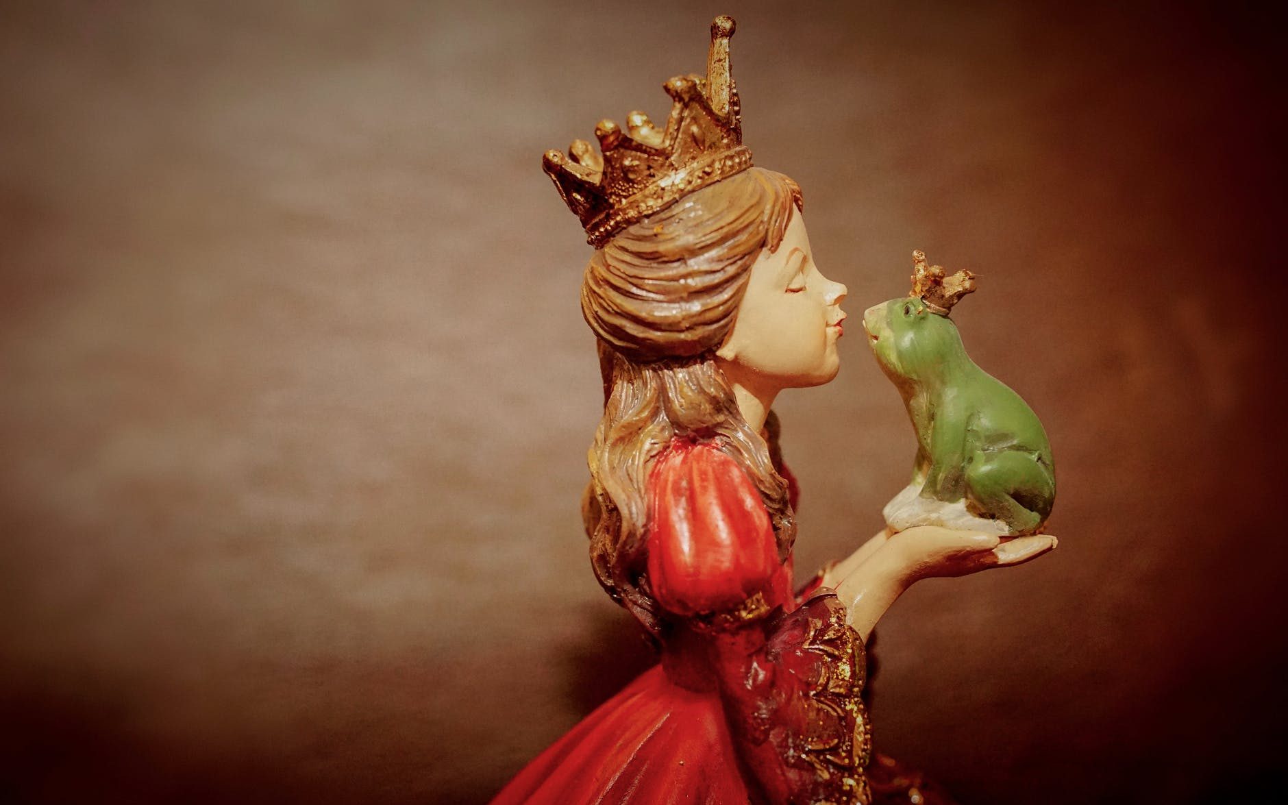 woman wearing crown holding frog figurine